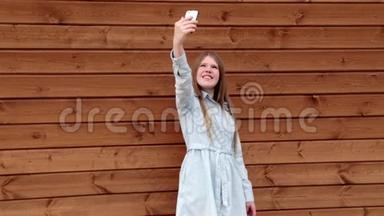 快乐的白种人少女在手机木制背景上自拍